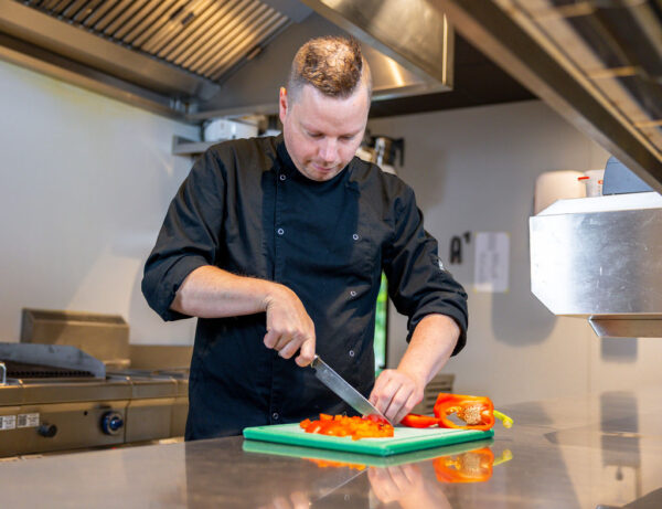 Restaurant Buck Bar Kitchen in Boskoop, chef Viktor Vurens TOPPR van mei in de keuken aan het snijden van tomaten